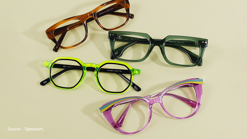 A flat lay of four colourful and trendy low prescription eyeglasses: brown rectangle, green square, neon yellow hexagonal, and purple cat-eye frames.