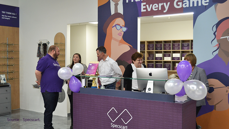 Staff members and customers interact at the main counter of a Specscart store, providing service and consultation for those seeking to purchase low prescription glasses.