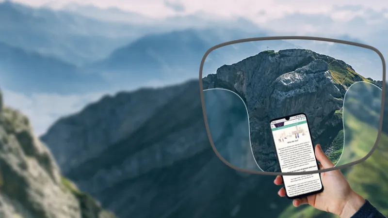 View through a varifocal lens showing a clear mountain in the distance and a sharp smartphone screen in the foreground.
