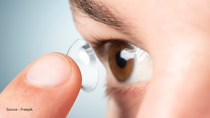 Extreme close-up view of a person applying a toric contact lens to their eye, which is a treatment option for correcting the blurred vision caused by astigmatism.