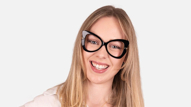 Smiling woman wearing oversized, thick-rimmed black butterfly glasses.