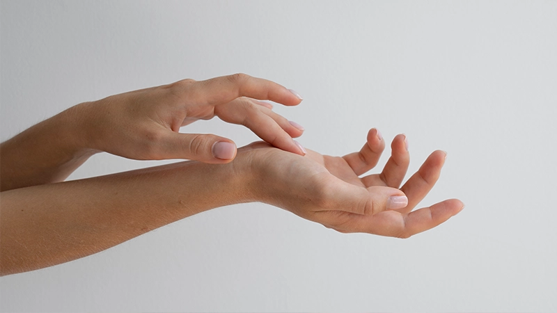 Close-up of a person's wrist and hands to check vein color, a method used to identify cool or warm skin undertones.