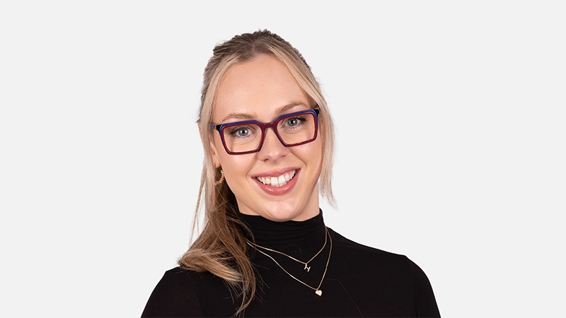 Smiling woman with blonde hair wearing blue and red gradient frames that complement her cool skin undertone.