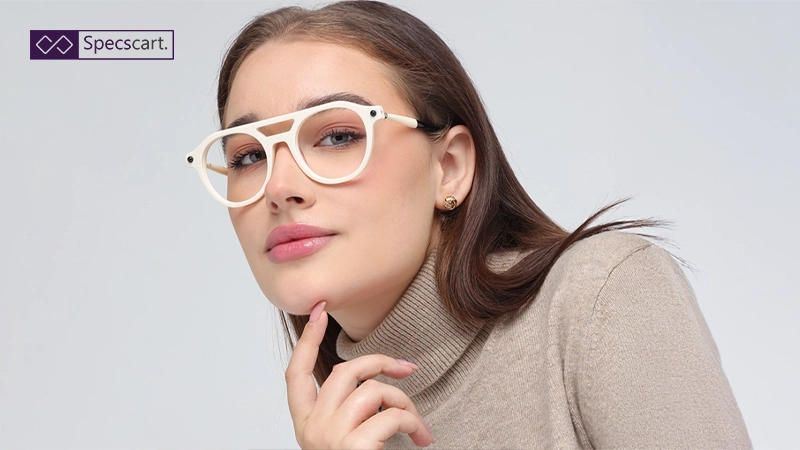 A woman wearing oversized white double-bridge pilot glasses and a beige turtleneck sweater.