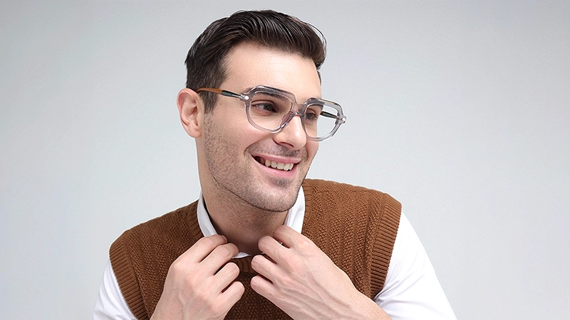 Smiling man in a brown vest wearing clear geometric glasses, representing a modern, subtle, and approachable personality.