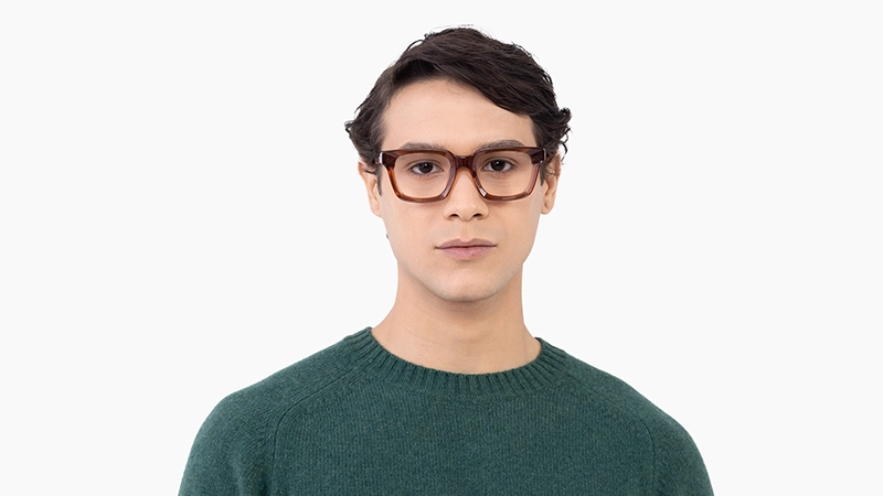 Man in a green sweater wearing brown tortoiseshell square glasses, conveying a reliable and down-to-earth personality.
