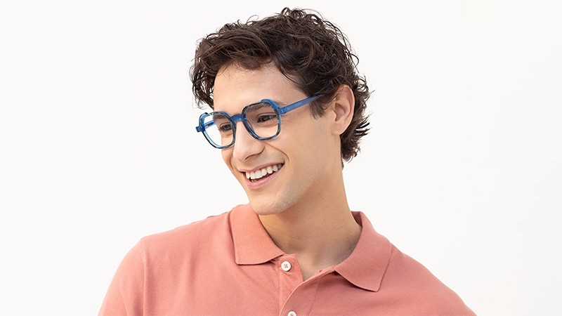 Smiling man wearing blue geometric glasses, representing a calm and trustworthy personality through color psychology.