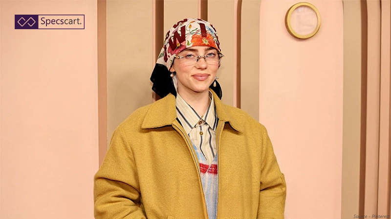 Get the Look in Glasses & Sunglasses: Billie Eilish Edition Celebrity Billie Eilish wearing thin, rimless rectangular glasses paired with a colourful headscarf and a yellow coat.