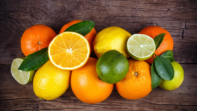 Assorted citrus fruits on a wooden table, providing vitamin C as a top food for healthy eyes.