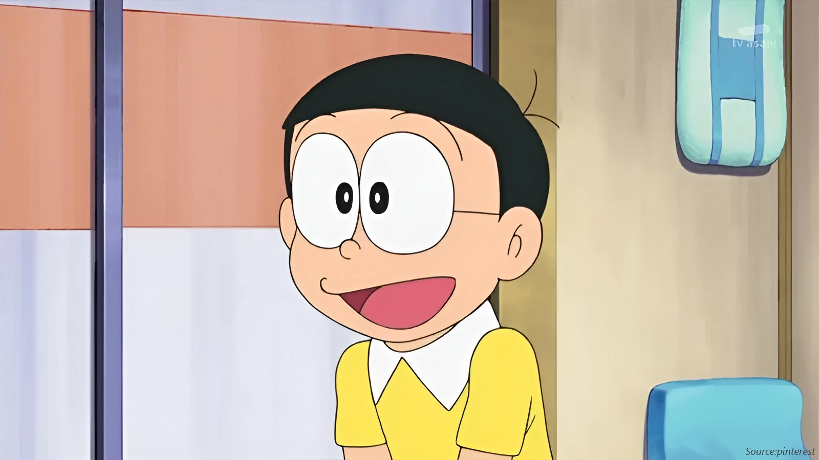 The smiling anime character Nobita Nobi from Doraemon is shown in a close-up. He wears a yellow shirt with a white collar and his thin-framed, round prescription glasses.