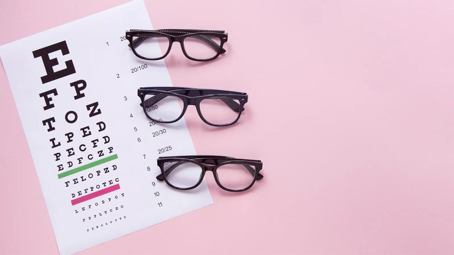 A Snellen eye chart next to three pairs of black-rimmed glasses on a pink background, representing an eye examination.