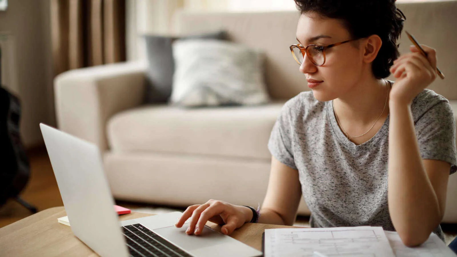 A woman wearing glasses works on a laptop, demonstrating how protective eyewear can reduce blue light exposure during long periods of screen use.