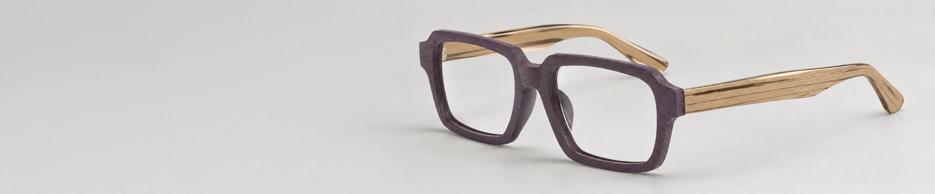 Wooden Glasses Round wooden-finish glasses resting on a polished timber stump, showcasing the natural grain texture and eco-friendly style of the frames.