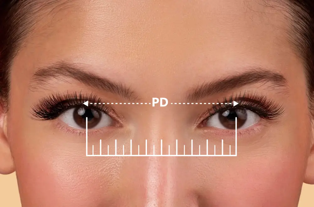 Image showing a person's eyes with a dashed line connecting the centre of their pupils labeled 'PD', and a ruler graphic below, demonstrating the process of measuring pupillary distance for glasses.