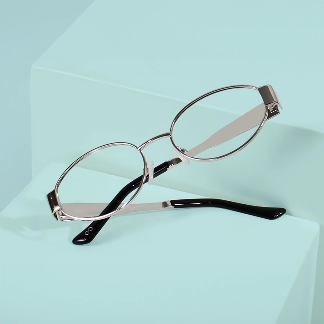 Silver Glasses Silver metal oval glasses with black temple tips displayed on minimalist mint green pedestals.