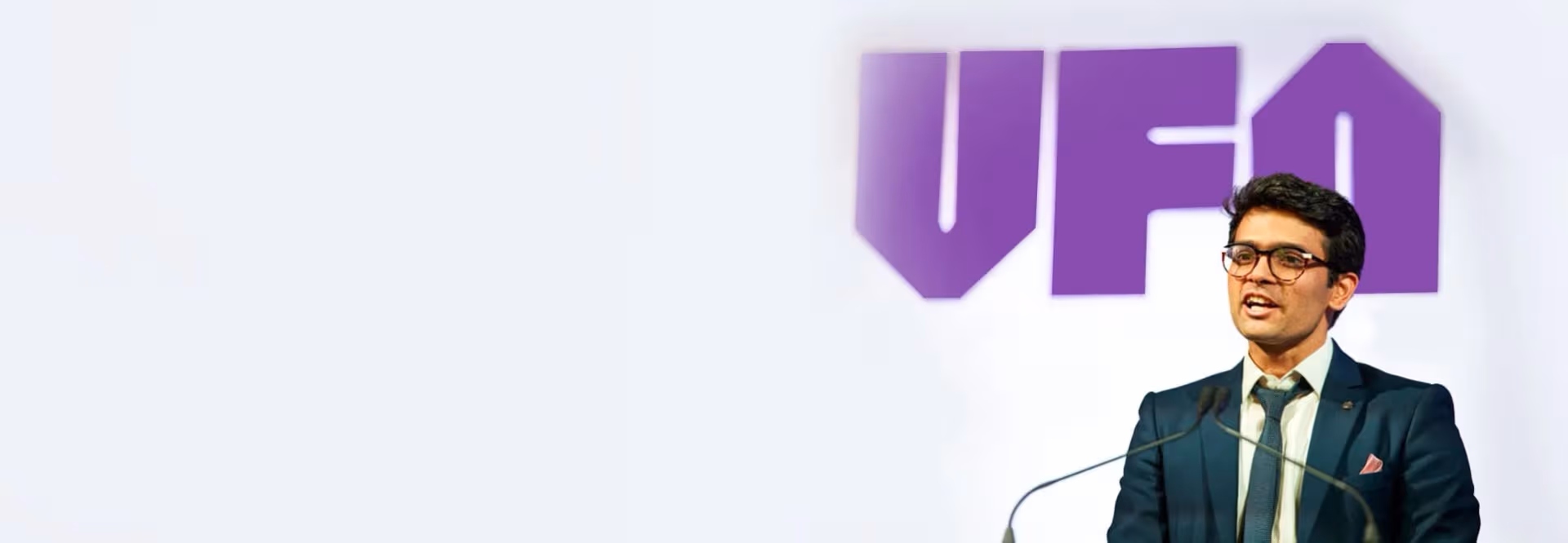 Sid Sethi, Specscart’s founder, giving a speech in formal attire at the Venture Further Awards, University of Manchester. The background features a large purple VFA logo and event branding, alongside an Excellent Trustpilot rating on the left.
