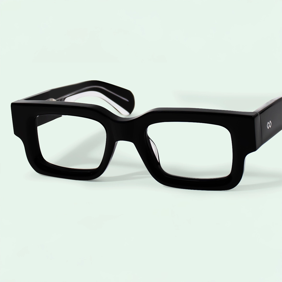 Thick Frame Glasses Close-up of stylish, bold, thick-framed square glasses in glossy black on a pale background.