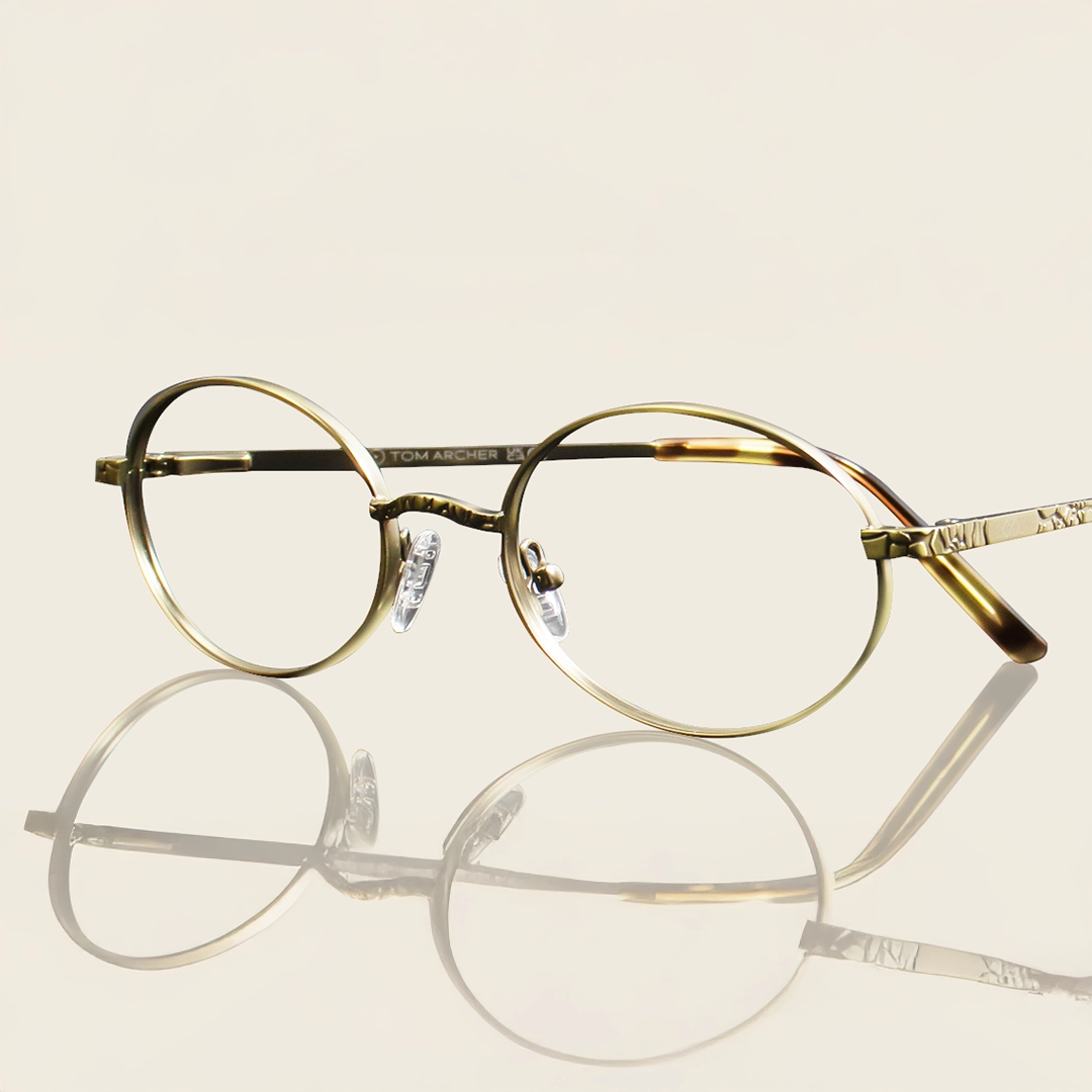 Elegant, vintage-style round glasses with thin, antique gold metal frames and tortoiseshell accents on the temples.