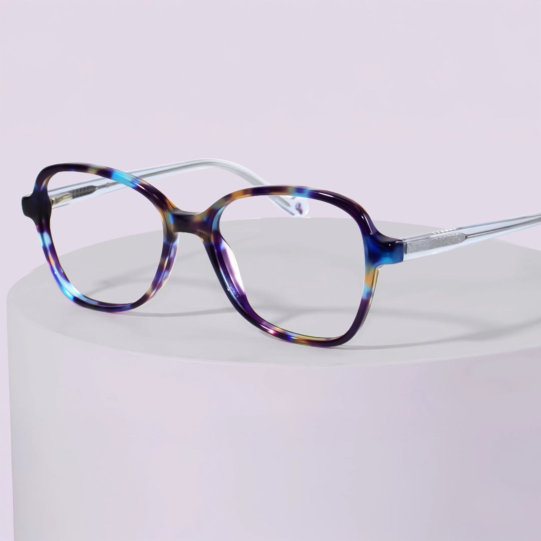 Multi Colour Glasses Oversized, rounded square glasses with unique, bold multicolour frames featuring blues, purples, and yellows, set on a light lavender background.
