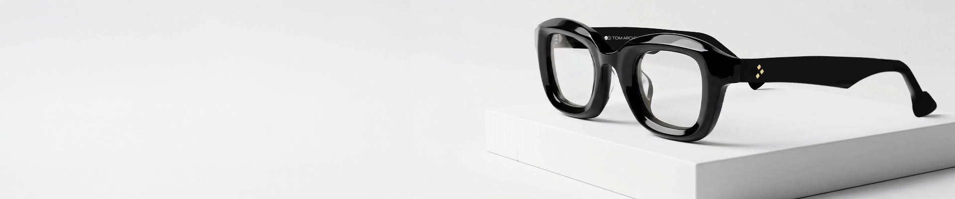 A close up image of black rectangular eyeglasses featuring a chunky black acetate frame placed on a textured stone surface. The image has content that says black glasses and a tagline. It also has a discount offer by Specscart and Trustpilot reviews.