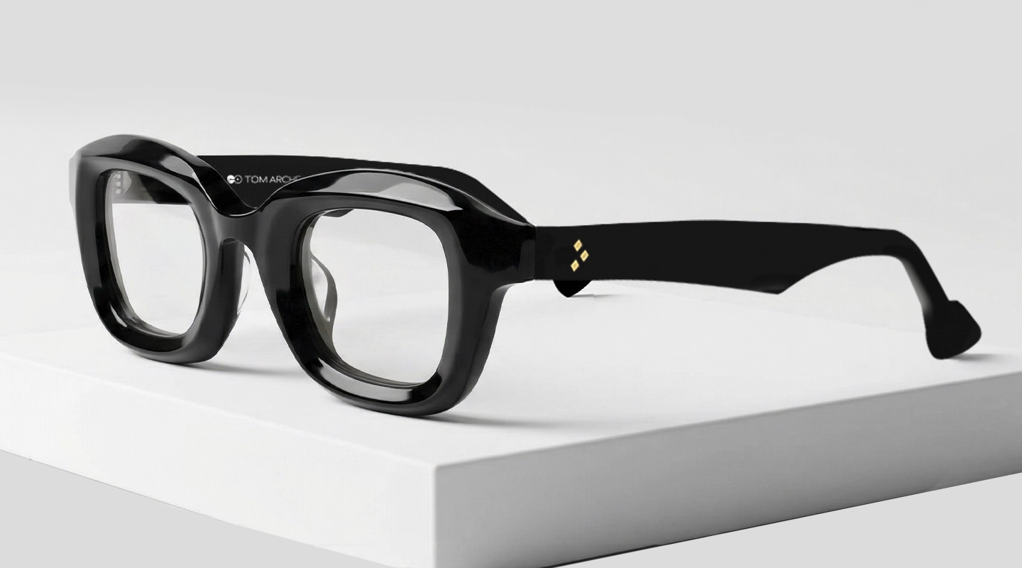 A close up image of black rectangular eyeglasses featuring a chunky black acetate frame placed on a textured stone surface. The image has content that says black glasses and a tagline. It also has a discount offer by Specscart and Trustpilot reviews.