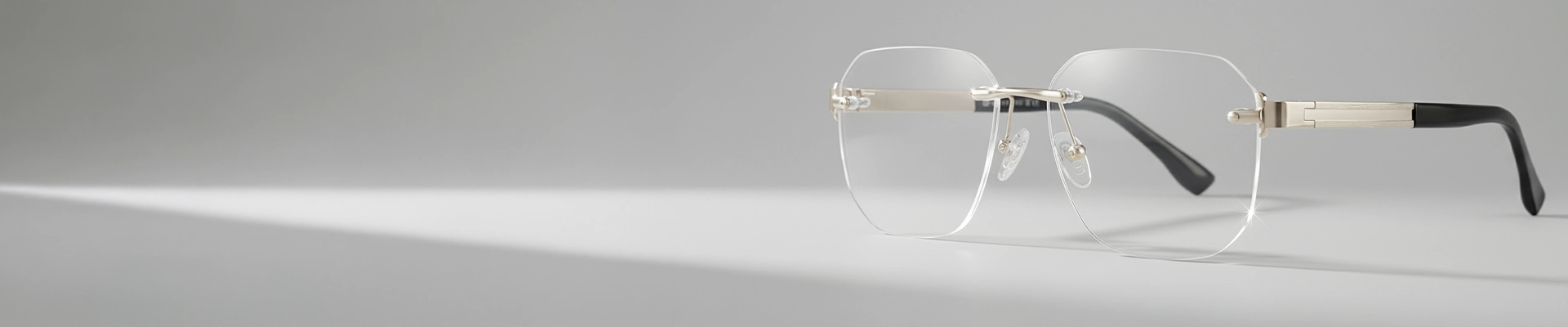 Minimalist rimless eyeglasses with rectangular lenses, silver bridge and temples, and black temple tips, shown on a light grey background