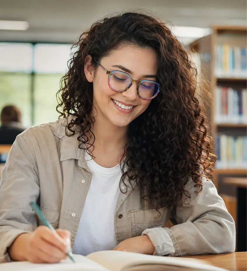 Smiling woman with curly hair wearing Specscart round blue light glasses, showcasing the protective blue lens reflection while using a smartphone.