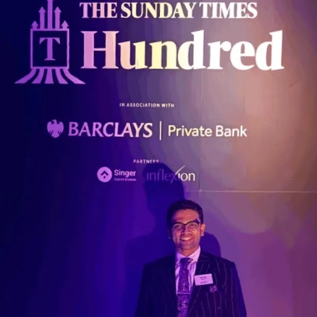 Specscart Founder Sid Sethi standing in front of a large event backdrop for The Sunday Times Hundred, featuring the logos of Barclays Private Bank and other partners. The image celebrates Specscart's recognition in The Sunday Times Seven Hottest Start-ups to Watch for companies led by founders under 35.
