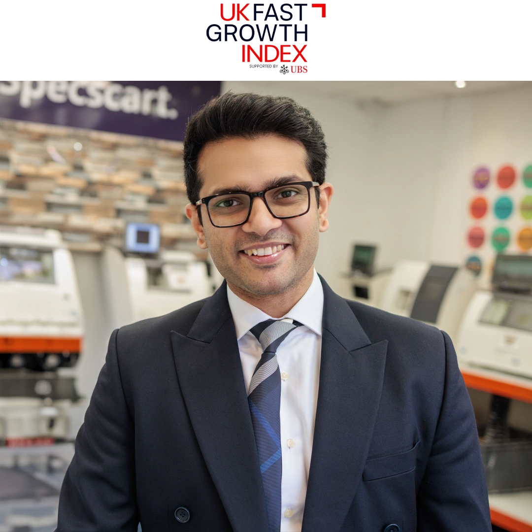 Specscart Founder Sid Sethi standing in front of a large event backdrop for The Sunday Times Hundred, featuring the logos of Barclays Private Bank and other partners. The image celebrates Specscart's recognition in The Sunday Times Seven Hottest Start-ups to Watch for companies led by founders under 35.