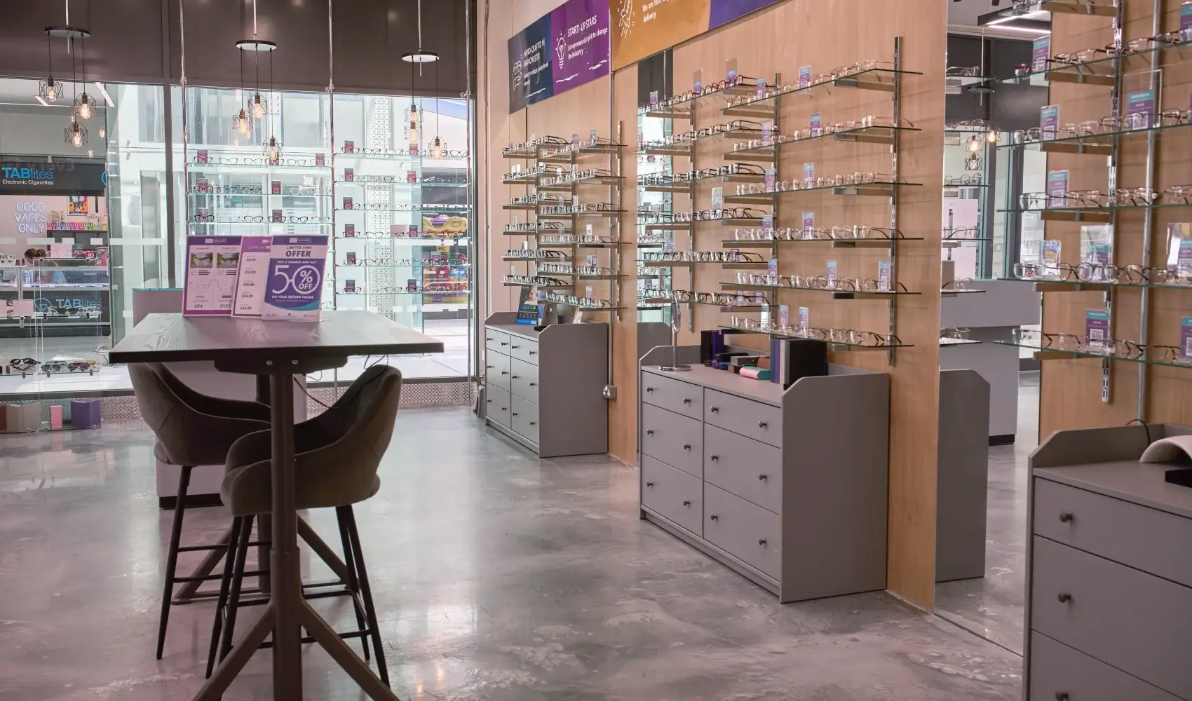 Specscart Walkden storefront with a prominent glowing purple sign and a digital window display advertising 24-hour dispatch on quality eyewear.