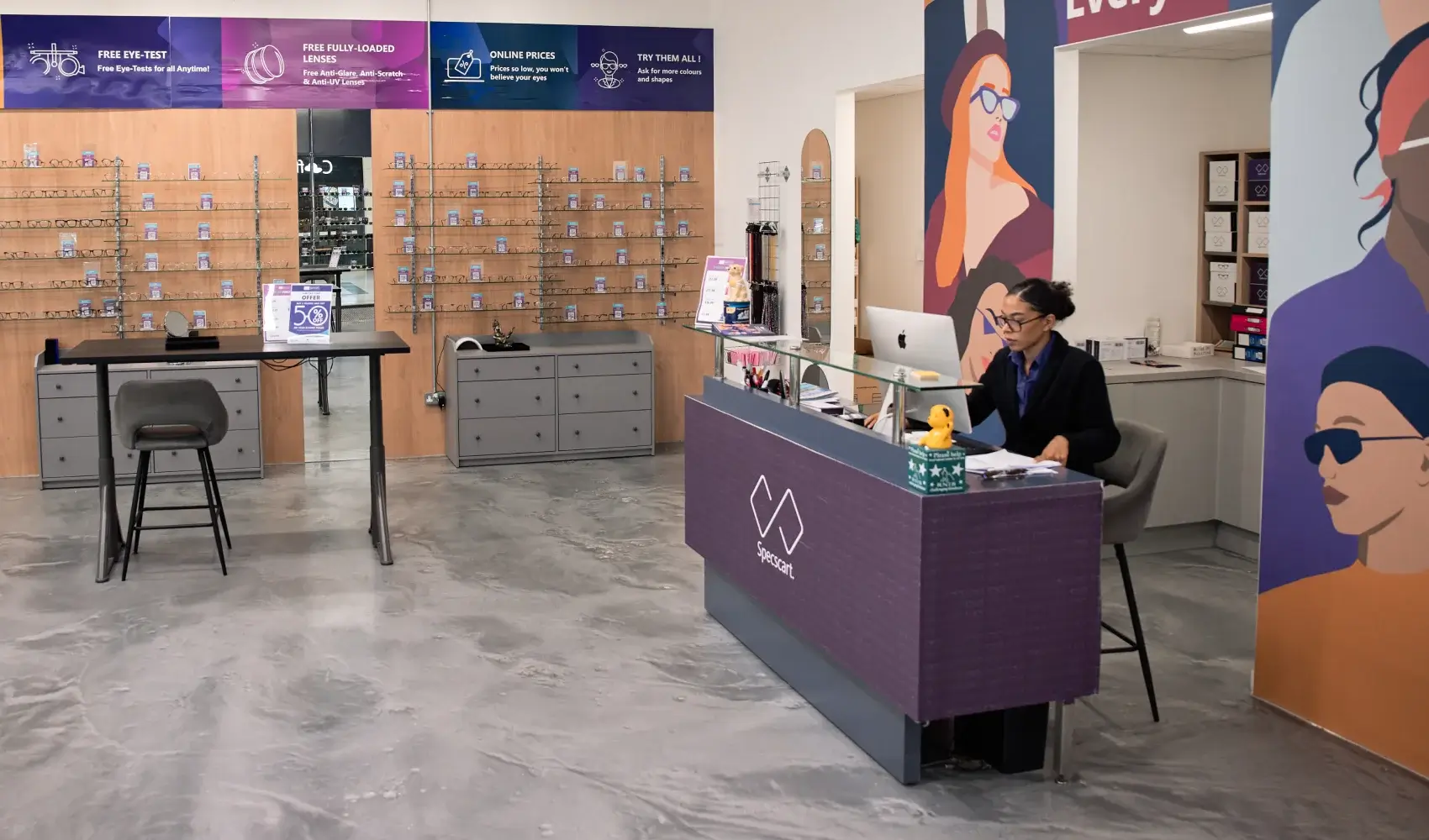 Vibrant Specscart Walkden interior featuring a purple bicycle wall mount, colourful mural, and friendly staff at the service counter with balloons.