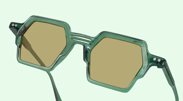 A close-up of premium black-framed pilots with polarised lenses, displayed on a geometric white block against a soft, bright background.