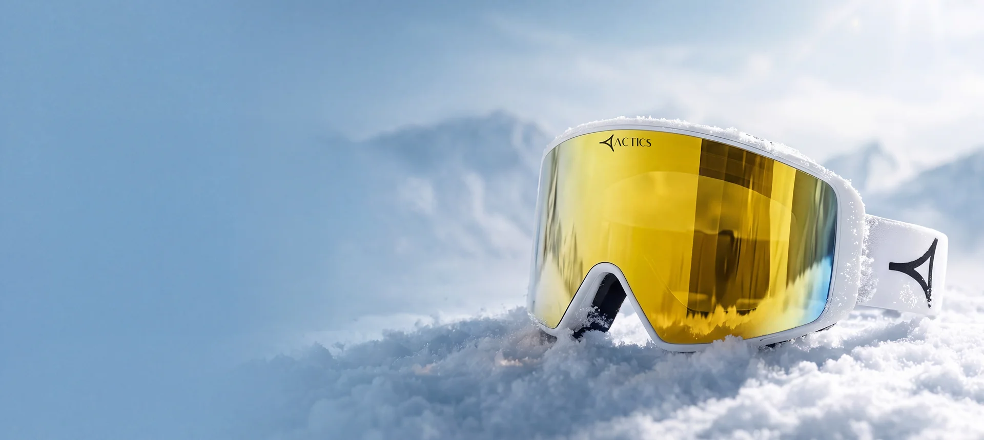 Ski goggles with mirrored golden lenses featured prominently against a snowy mountain backdrop. The reflective lenses show the rugged snow-capped peaks and cloudy sky, while the dark strap displays the Specscart Actics branding in white.