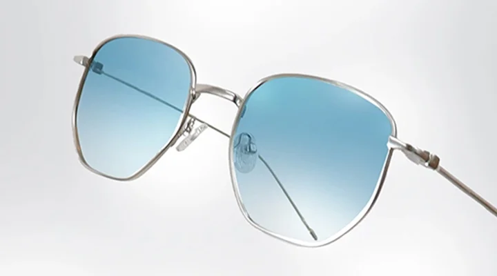 Silver Sunglasses A pair of lightweight silver sunglasses with blue-tinted lenses, displayed at an angle to highlight the sleek metal frame and minimalist design.