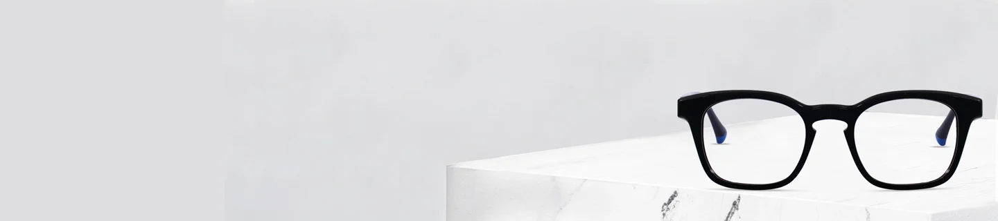 Stylish black keyhole bridge glasses with subtle blue temple tips placed on a marble block, highlighting Specscart’s modern eyewear design.